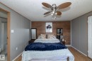 Interior space featuring wood-finish flooring, a textured ceiling, a ceiling fan with integrated lighting, and a prominent wood-panel accent wall - 143 48 3400 Street W, Stony Plain, AB 