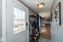 Entryway featuring a partially glazed door with grid panes, a ceiling-mounted light fixture, and wood-finish flooring extending into the interior - 
