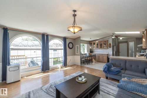 Open concept living space featuring wood-finish flooring, three arched windows, and a ceiling-mounted light fixture - 143 48 3400 Street W, Stony Plain, AB 