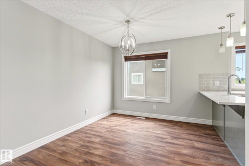 Open-concept dining area with wood-finish flooring, a contemporary chandelier, and a large window - 47 330 Bulyea Road, Edmonton, AB - Indoor