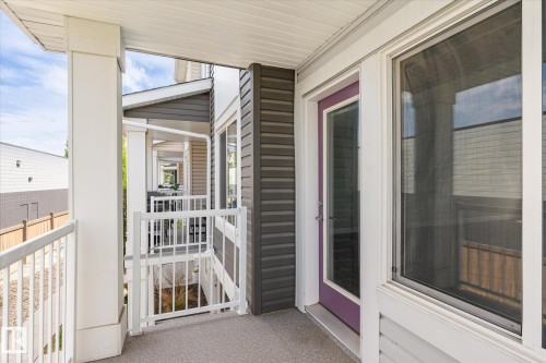 Exterior balcony featuring a textured concrete surface, white aluminum railings, and a purple-framed glass door - 47 330 Bulyea Road, Edmonton, AB - Outdoor With Balcony With Exterior