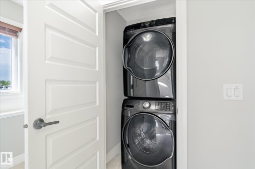 Integrated stacked washer and dryer unit within a dedicated closet - 47 330 Bulyea Road, Edmonton, AB - Indoor Photo Showing Laundry Room