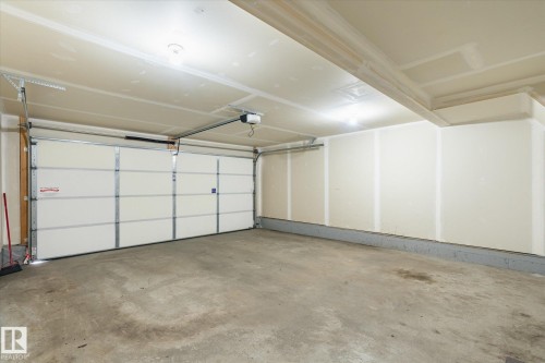 Spacious garage featuring a sectional overhead door with an automatic opener, concrete flooring, and recessed ceiling lighting - 47 330 Bulyea Road, Edmonton, AB - Indoor Photo Showing Garage