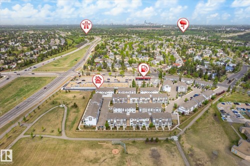 Aerial view showcasing a community of multi-story townhomes with light-colored siding and dark roofs, positioned near a multi-lane roadway - 47 330 Bulyea Road, Edmonton, AB - Outdoor With View