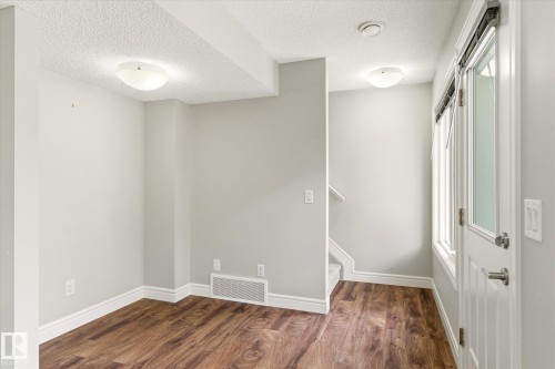 Entry area featuring wood-finish flooring, light gray walls, white baseboards, and a glass-paneled door with window blinds - 47 330 Bulyea Road, Edmonton, AB - Indoor Photo Showing Other Room