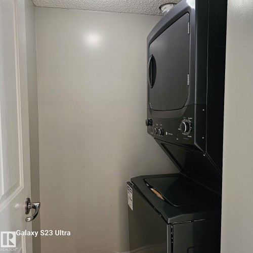 Dedicated laundry area featuring a stacked black washer and dryer unit - 99 13825 155 Avenue, Edmonton, AB 