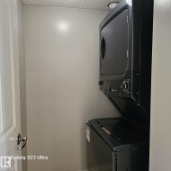 Dedicated laundry area featuring a stacked black washer and dryer unit - 