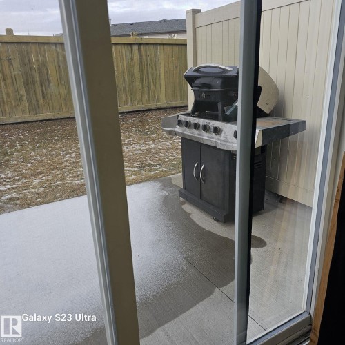 Exterior patio area featuring concrete flooring and a partial wooden fence - 99 13825 155 Avenue, Edmonton, AB 