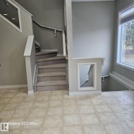 Carpeted staircase with white railings and an integrated wall niche, complemented by neutral wall paint and tile flooring - 