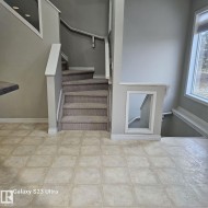 Tiled flooring extending to a carpeted staircase with white railings - 