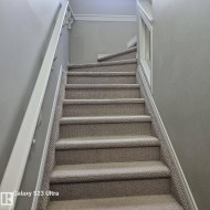 Carpeted staircase featuring a painted handrail and white trim details - 