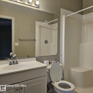 Bathroom featuring a white vanity with an integrated sink, chrome faucet, and overhead bar lighting - 