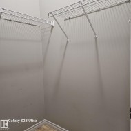 Walk-in closet featuring light gray walls, white wire shelving, and trim - 