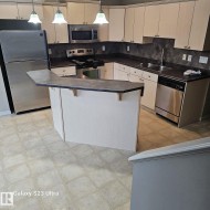 Well-appointed kitchen featuring light-toned cabinetry, dark countertops, and a full suite of stainless steel appliances including a refrigerator, range, microwave, and dishwasher - 