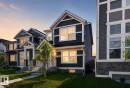 Two-story residence featuring dark blue siding, white trim, a gabled roofline, stone veneer accents, and a manicured lawn - 749 Southfork Drive, Leduc, AB 