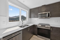 Modern kitchen featuring dark wood-finish cabinetry, white subway tile backsplash, and light-toned countertops - 
