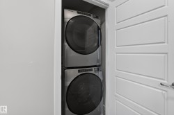 Stackable laundry appliances within a dedicated closet, featuring a white paneled door with a polished chrome handle - 