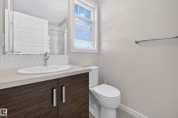 Bathroom featuring a wood-finish vanity with an undermount sink, a white subway tile backsplash, and a window with natural light - 