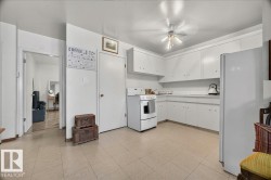 Kitchen featuring white cabinetry, white countertops, a white freestanding range, and a full-size white refrigerator - 