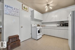 Bright kitchen featuring extensive white cabinetry, a white electric range, white countertops, a stainless steel refrigerator, and neutral tile flooring - 