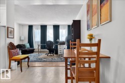 Expansive living area with wood-finish flooring and multiple windows, featuring an adjacent dining space with tile flooring - 