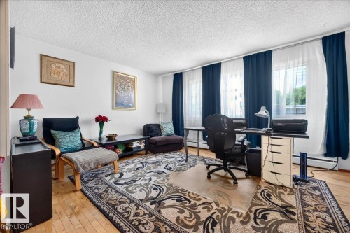 Bright interior space with wood-finish flooring, white walls, and multiple windows - 33 10230 122 Street, Edmonton, AB 
