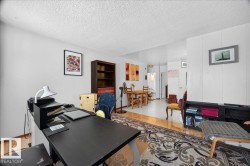 Open concept room featuring a textured ceiling, a mix of wood-finish flooring and light-toned tile, and neutral wall tones - 