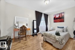 Spacious room featuring wood-finish flooring, a contemporary ceiling light fixture, and large windows with privacy drapes - 