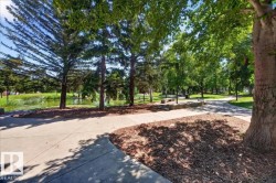 Paved walking paths wind through mature trees and landscaped grounds, bordering a tranquil body of water - 