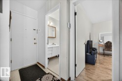 Entryway featuring a white door with brass hardware, tile flooring, and a doorway leading to a bathroom - 