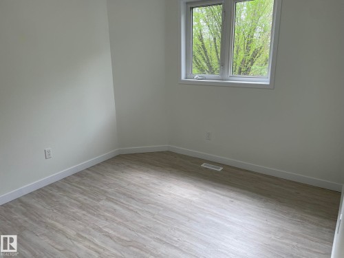 Bright room featuring wood-finish flooring, crisp white walls, and a large window - 2 1295 Carter Crest Road, Edmonton, AB - Indoor Photo Showing Other Room