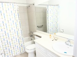 Bathroom featuring a white vanity with integrated sink, chrome faucet, and a large wall mirror - 