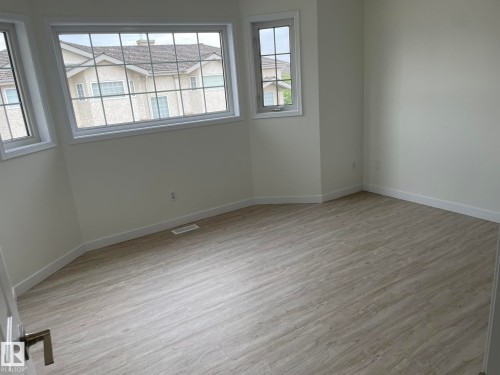 Spacious room featuring light wood-finish flooring, crisp white walls, and multiple windows with white trim - 2 1295 Carter Crest Road, Edmonton, AB - Indoor Photo Showing Other Room