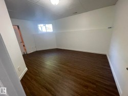 Room featuring wood-finish flooring, white walls, a single window, and a flush mount ceiling light fixture - 