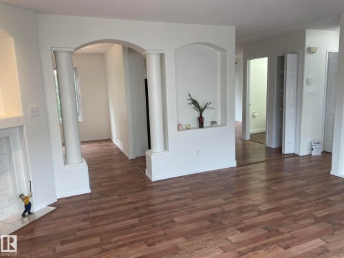 Archways and decorative columns define the space, complemented by neutral wall tones and wood-finish flooring - 2 1295 Carter Crest Road, Edmonton, AB - Indoor Photo Showing Other Room