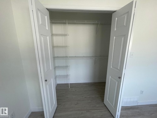 Walk-in closet with double white paneled doors, wire shelving, and wood-finish flooring - 2 1295 Carter Crest Road, Edmonton, AB - Indoor With Storage