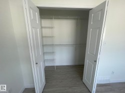 Walk-in closet with double white paneled doors, wire shelving, and wood-finish flooring - 