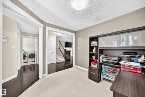 Carpeted room with a built-in dark wood-finish desk and shelving unit - 3433 Goodridge Link Link, Edmonton, AB 