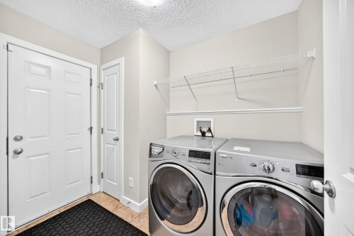 Dedicated laundry area featuring a tile floor, white panel doors, and overhead wire shelving - 3433 Goodridge Link Link, Edmonton, AB 