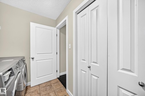 Utility area featuring light beige walls, textured ceiling, and tiled flooring - 3433 Goodridge Link Link, Edmonton, AB 