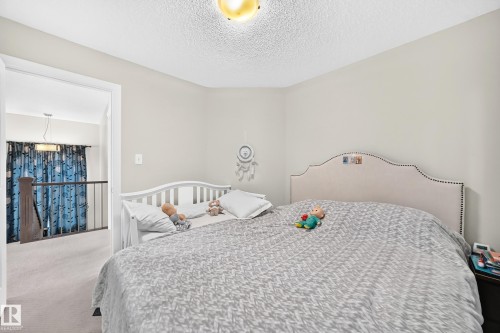 Carpeted room with light neutral wall paint and a textured ceiling - 3433 Goodridge Link Link, Edmonton, AB 