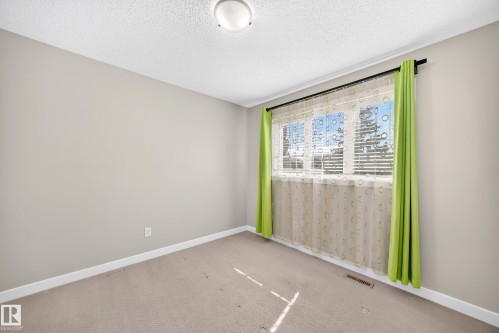 Neutral-toned walls and carpeting define this room, featuring a window with horizontal blinds and a window treatment rod - 3433 Goodridge Link Link, Edmonton, AB 