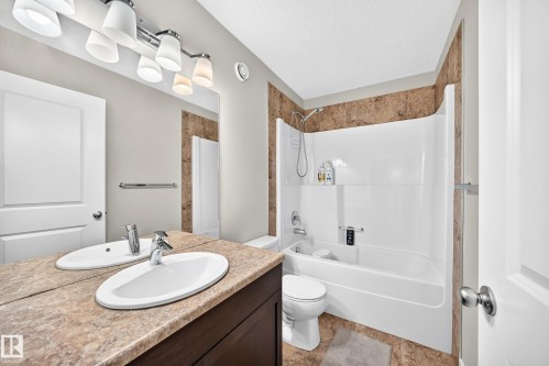 Bathroom featuring a dual vanity with undermount sinks and a stone-finish countertop - 3433 Goodridge Link Link, Edmonton, AB 