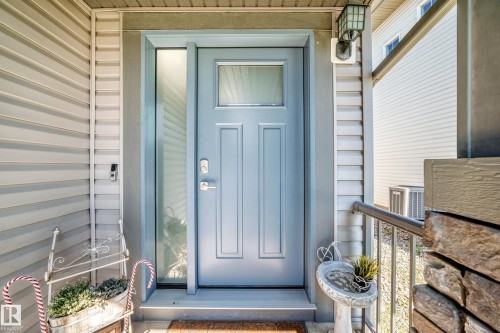 Entryway featuring a panel door with an upper window, a full-length sidelight, and an overhead porch light - 3433 Goodridge Link Link, Edmonton, AB 