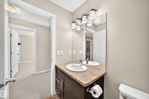 Bathroom vanity featuring a single sink, neutral countertop, and dark wood cabinetry with modern hardware - 3433 Goodridge Link Link, Edmonton, AB 