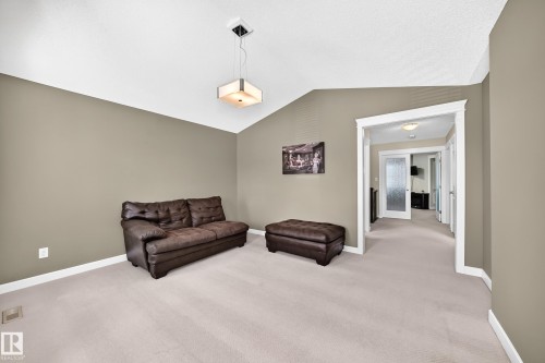 Carpeted living space with vaulted ceiling and a contemporary pendant light fixture - 3433 Goodridge Link Link, Edmonton, AB 