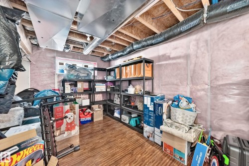 Unfinished basement featuring exposed ceiling joists, visible ductwork, a small window, and wood-finish flooring - 3433 Goodridge Link Link, Edmonton, AB 
