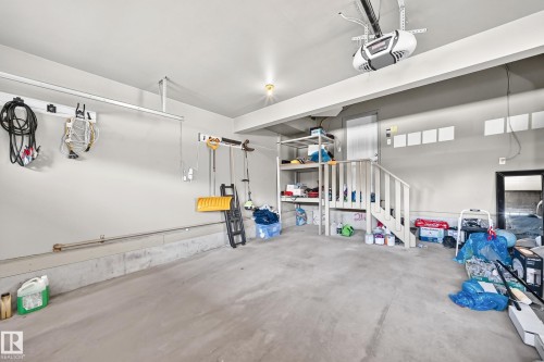 Spacious garage featuring a concrete floor, built-in overhead storage system, and interior access door - 3433 Goodridge Link Link, Edmonton, AB 