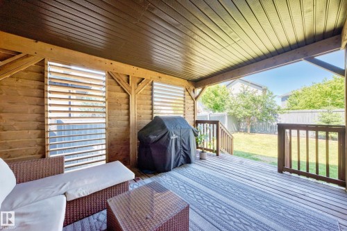 Covered wood-plank deck featuring a slatted privacy wall, wood-finish railing, and exposed beam ceiling - 3433 Goodridge Link Link, Edmonton, AB 