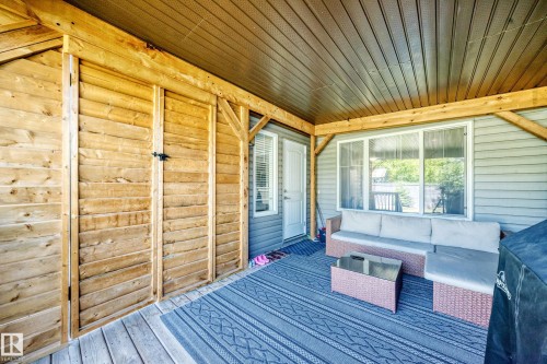 Covered patio with a wood-finish plank ceiling and matching wood-finish beam supports - 3433 Goodridge Link Link, Edmonton, AB 